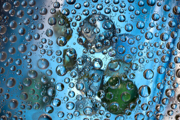 Transparent drops of water are located against a blue background with green and  blue balls. Abstract fantasy. 3D render.