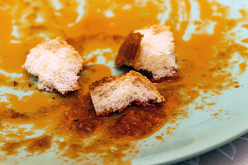 White bread pieces dipped in leftover tomato meat sauce on a plate