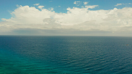 Sea surface with waves against the blue sky with clouds, aerial view. Water cloud horizon background. Blue sea water with small waves against sky.