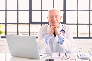 Portrait of smiling male doctor sitting at desk in doctor's room