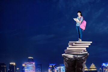 Female student using a tablet on a pile of book