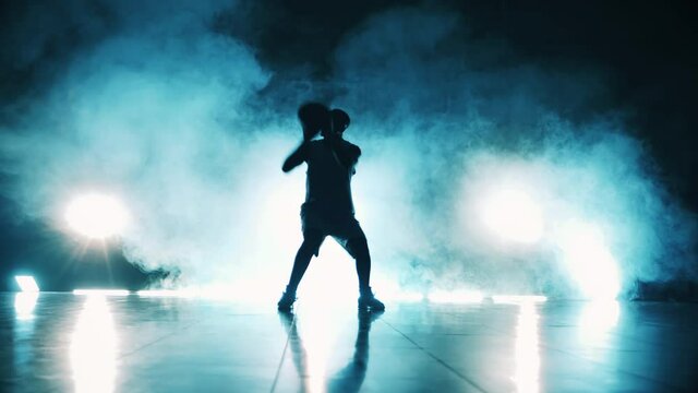 Dark room with clouds of smoke and a man throwing a basketball ball