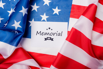 Fototapeta na wymiar Top view of card with memorial day lettering on american flag