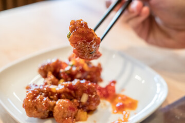 Chopsticks holding Korean fried chicken.