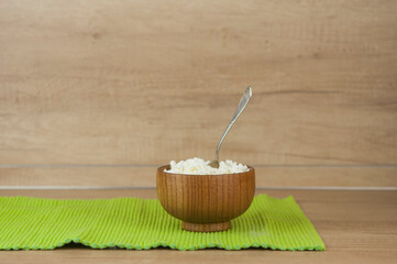 dairy product cottage cheese in brown wooden bowl with spoon on wood kitchen table