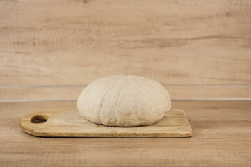 Risen or proved yeast dough for bread or pizza on wooden surface
