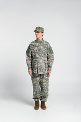 Woman in military clothes standing on grey background