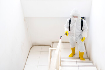 Male worker making disinfection in office stairs