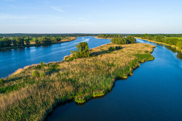 The Odra River in Poland, in a section of the Śląskie Voivodeship, photographed during the golden hour. The beautiful blue color of the river and shades of yellow and green on land.
