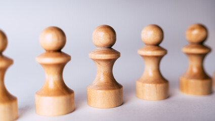 Close up of white wooden chess pieces. Row of white pawns on white background.