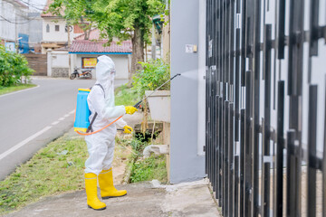 Male worker spraying fence with disinfectant