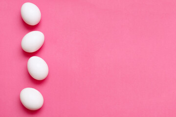 four chicken eggs on a bright pink background
