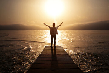 Fototapeta premium Man stretching hands while standing on the jetty