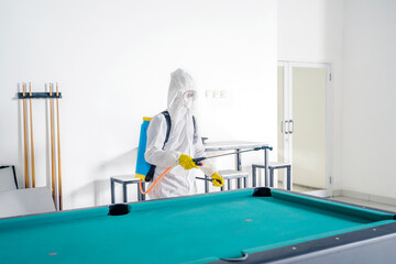 Worker clean billiard table with disinfectant spray