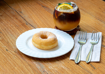 Donuts on white plate and orange coffee on wooden background