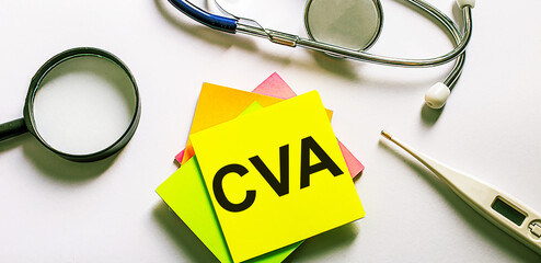 The word CVA is written on a bright sticker on a light background near a stethoscope, magnifying glass and an electronic thermometer. Medical concept