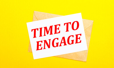 On a yellow background, an envelope and a card with the text TIME TO ENGAGE. View from above