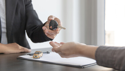 Car salesman gave the keys to the customers who signed the purchase contract legally, Successful completion of car sales, Purchase contract and key delivery.