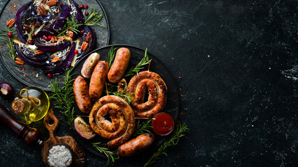 Set of fried barbecue sausages with rosemary and sauces. Top view. On a black stone background.