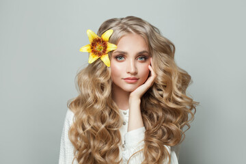 Attractive cheerful woman with healthy curly hair and yellow lily flower on white background