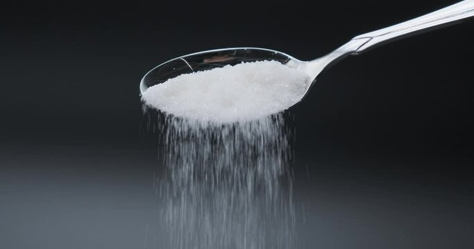 A full spoon of sugar. Sugar falling from spoon in slow motion 