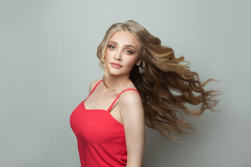 Young beautiful woman with long healthy hair in red dress on white background