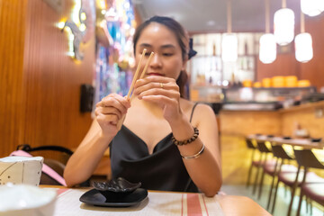 Asian woman waiting in sushi restaurant. Selective focus asian female boring waiting friends or food at restaurant.