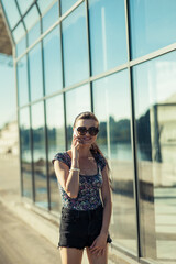 Fototapeta premium Sexy girl talking on the phone near the glass building