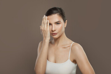 Serious woman in white t-shirt on brown background. Facial treatment, cosmetology and skin care concept