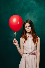 woman with a red balloon on a green background pink dress model