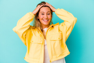 Young mixed race woman isolated on blue background laughs joyfully keeping hands on head. Happiness concept.