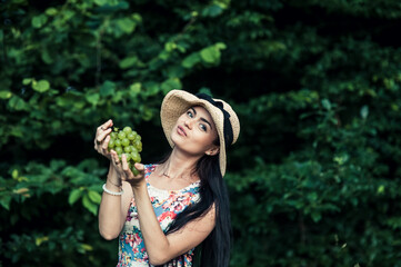 Girl on a picnic eats green grapes fruit.Cute brunette woman harvesting fruits on the farm. High quality photo