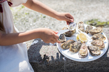 Eating fresh oysters just beside the oyster farm at Cancale, Brittany, France. Child hands holding oyster ready to eat.