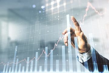Multi exposure of businessman hand presses on virtual creative financial chart hologram on blurred...