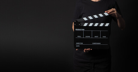 woman is holding black clapperboard or movie slate in studio shooting .It is use in video...