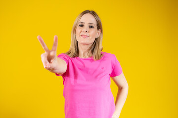 Fototapeta premium Beautiful young woman happy and excited expressing winning gesture. Successful pretty woman celebrating victory, triumphant over yellow background