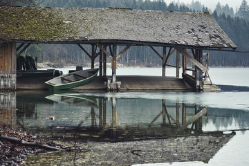 old wooden boats house on the river with a forest in the background