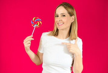 Young woman holding a big lollipop over isolated over pink background.