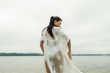 Fototapeta na wymiar Sexy girl in a white dress on a background of the lake.