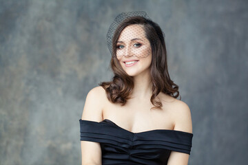 Perfect woman in black veil smiling on gray background, portrait