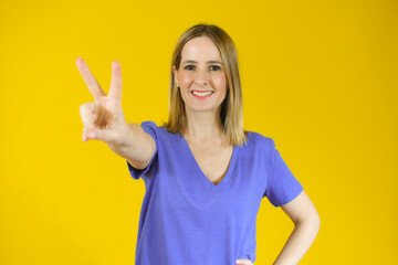 Beautiful young woman happy and excited expressing winning gesture. Successful pretty woman celebrating victory, triumphant over yellow background