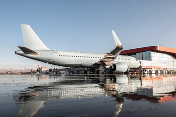 Passenger aircraft parked to a jet bridge with reflection in a puddle