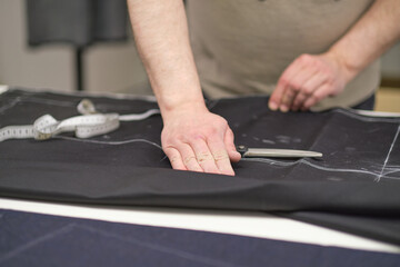 Dressmaker cutting dress fabric on sketch line. Fashion designer tailor or sewer in workshop studio designing new collection clothes. Business owner shop and entrepreneur concept