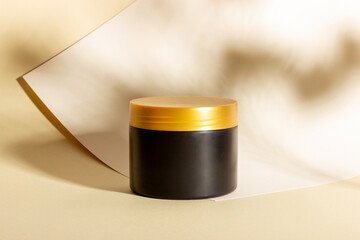 Cosmetic black bottle with body cream. Background with hard shadows. The concept of a beauty salon...
