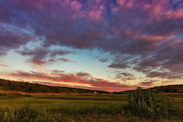 Fototapeta na wymiar Beautiful summer sunset over the meadow, against the backdrop of beautiful evening clouds