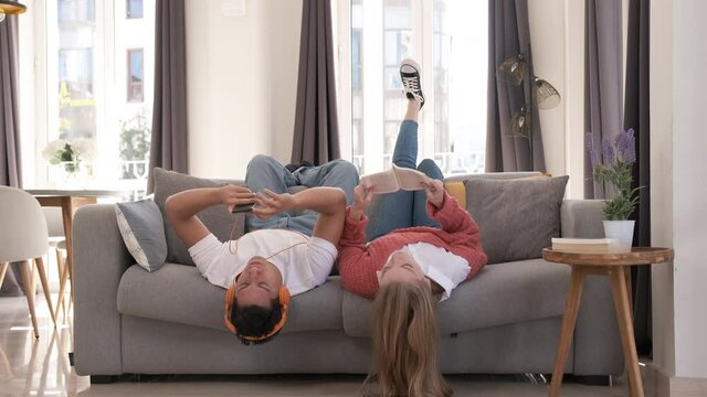 Young couple relaxing and spending time together while laying on the couch at home.