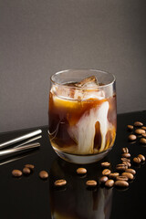 Cold brew coffee with milk in the glass drinking  on the black  background. Location vertical.