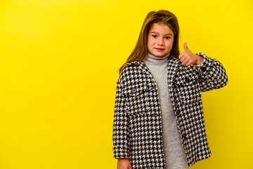 Little caucasian girl isolated on yellow background smiling and raising thumb up