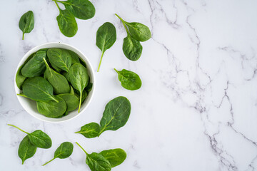 Fresh Organic Healthy Spinach Isolated in White Bowl Overhead Shot on Marble Light White Texture Table Background with Copy Space