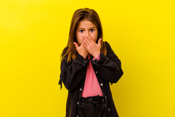 Little caucasian girl isolated on yellow background shocked covering mouth with hands.